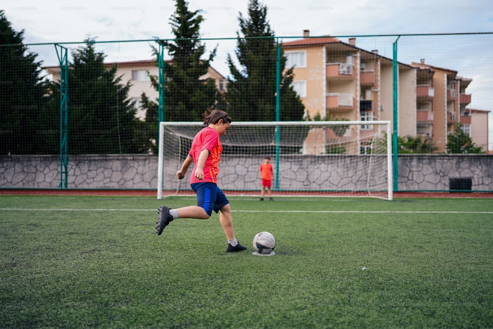 um jovem chutando uma bola de futebol em um campo
