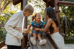 a man and two girls playing on a wooden slide