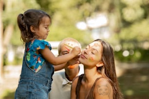 Una mujer sosteniendo a una niña con la cara pintada