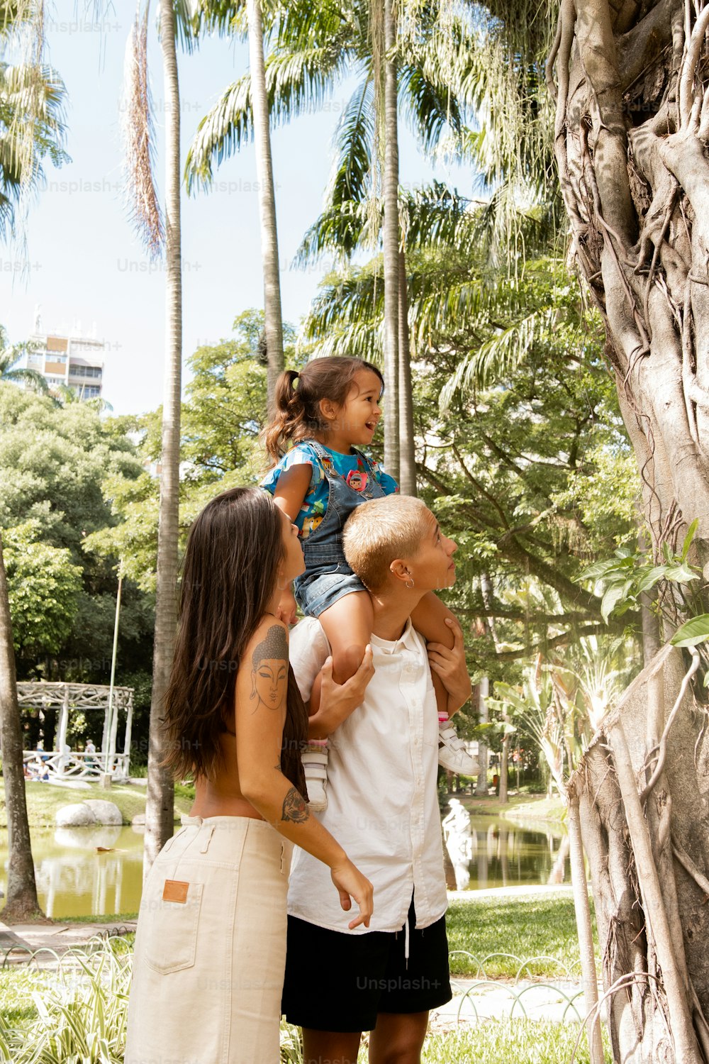 uma mulher e duas crianças em frente a uma árvore