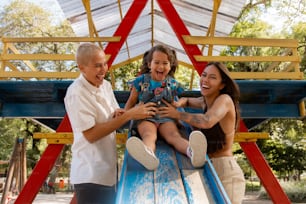 a man and two women sitting on top of a slide