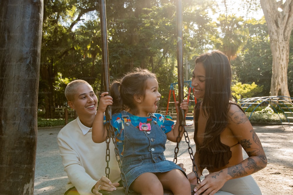 a woman and two children sitting on a swing