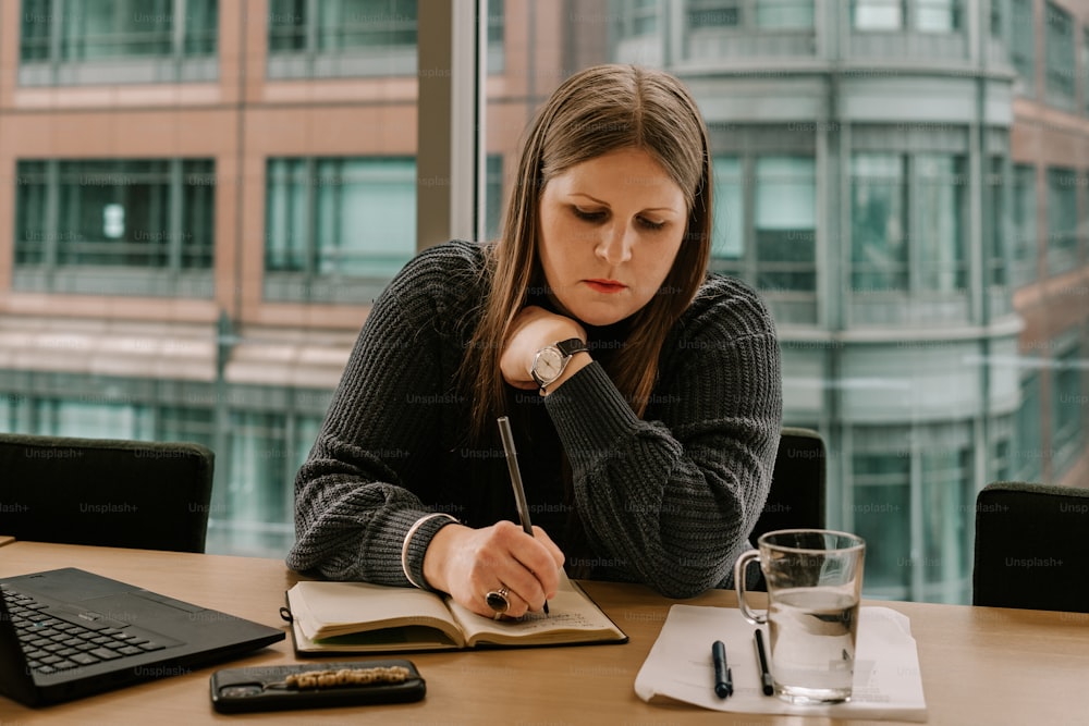 Une femme assise à une table avec un livre et un stylo