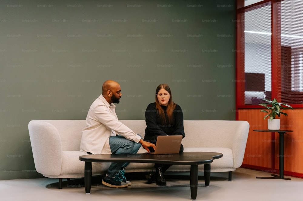 a man and a woman sitting on a couch with a laptop