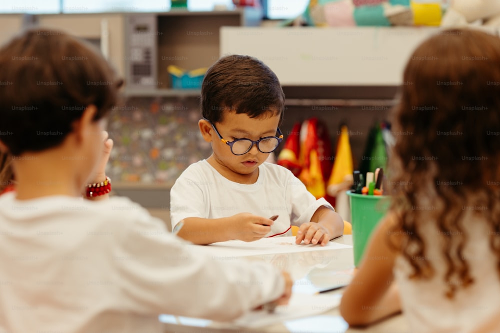 un jeune garçon assis à une table avec deux autres enfants