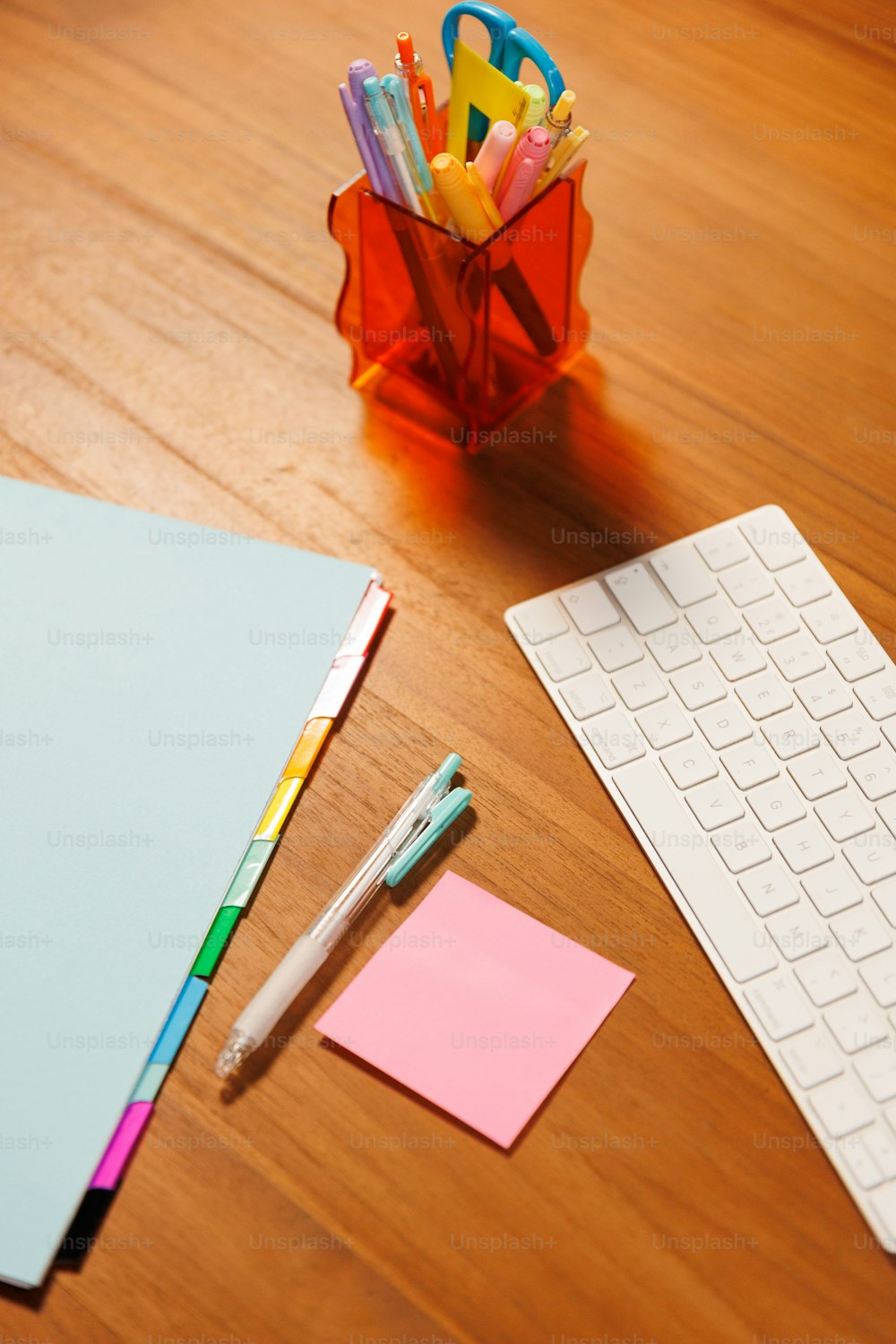una scrivania con tastiera, mouse, penne e post-it