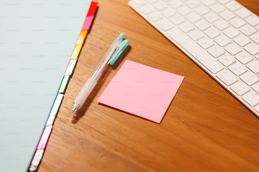 키보드 옆 책상 위에 놓여 있는 펜과 스티커 메모