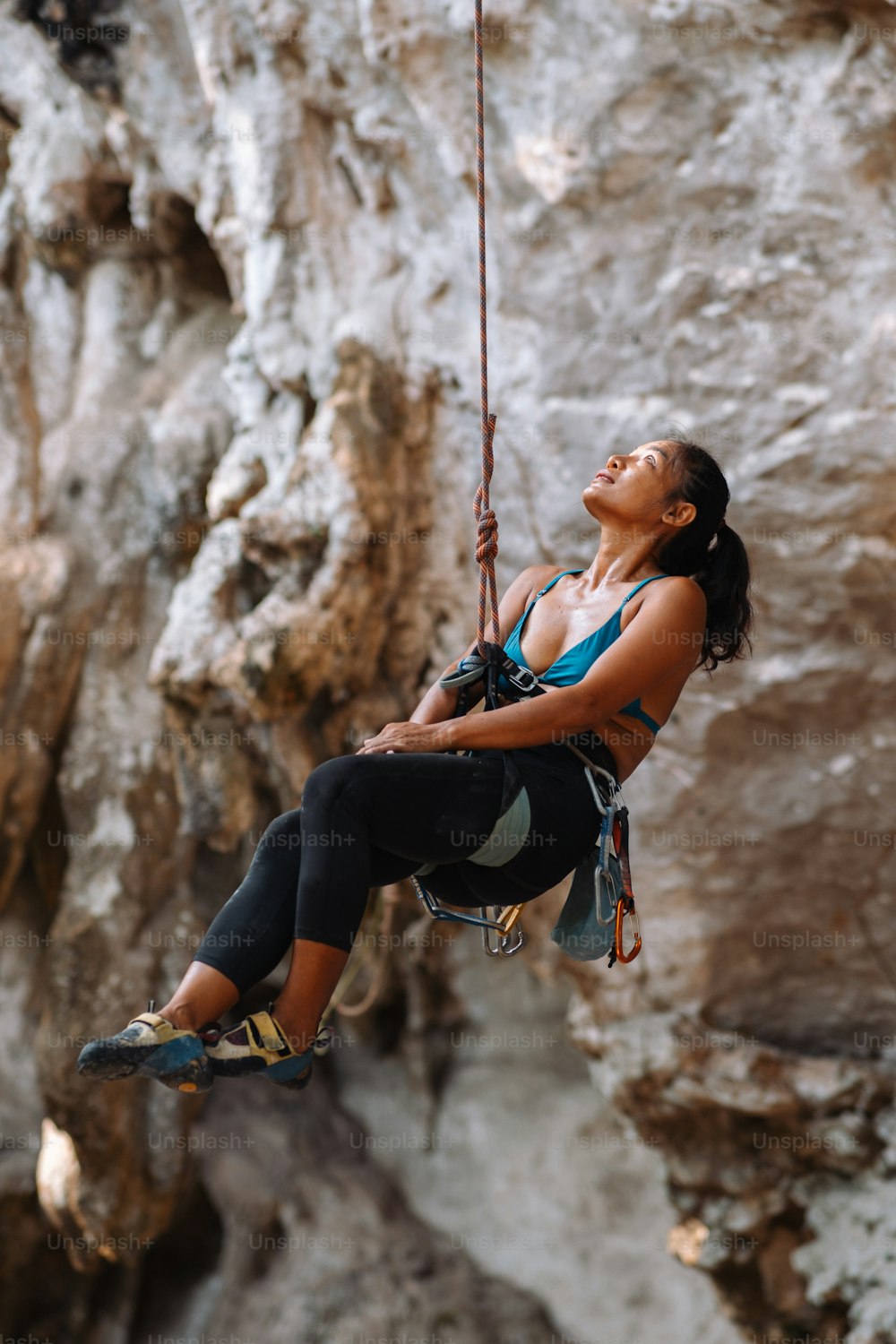a woman hanging from a rope in front of a cliff