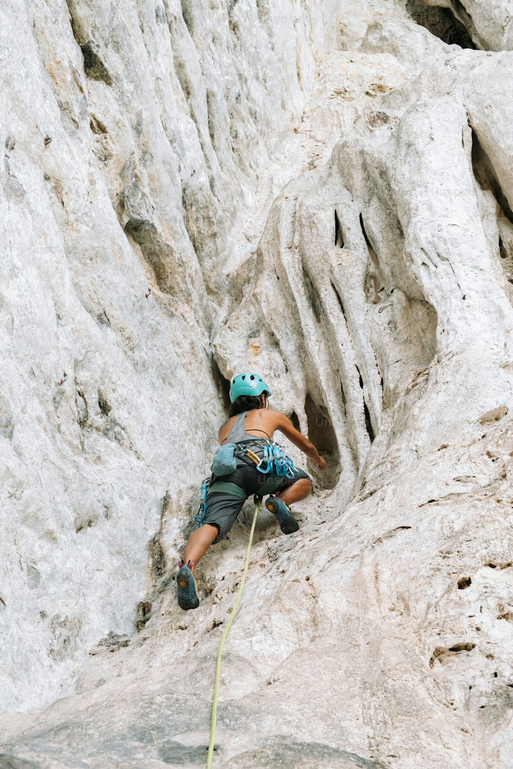 uma mulher subindo o lado de uma montanha