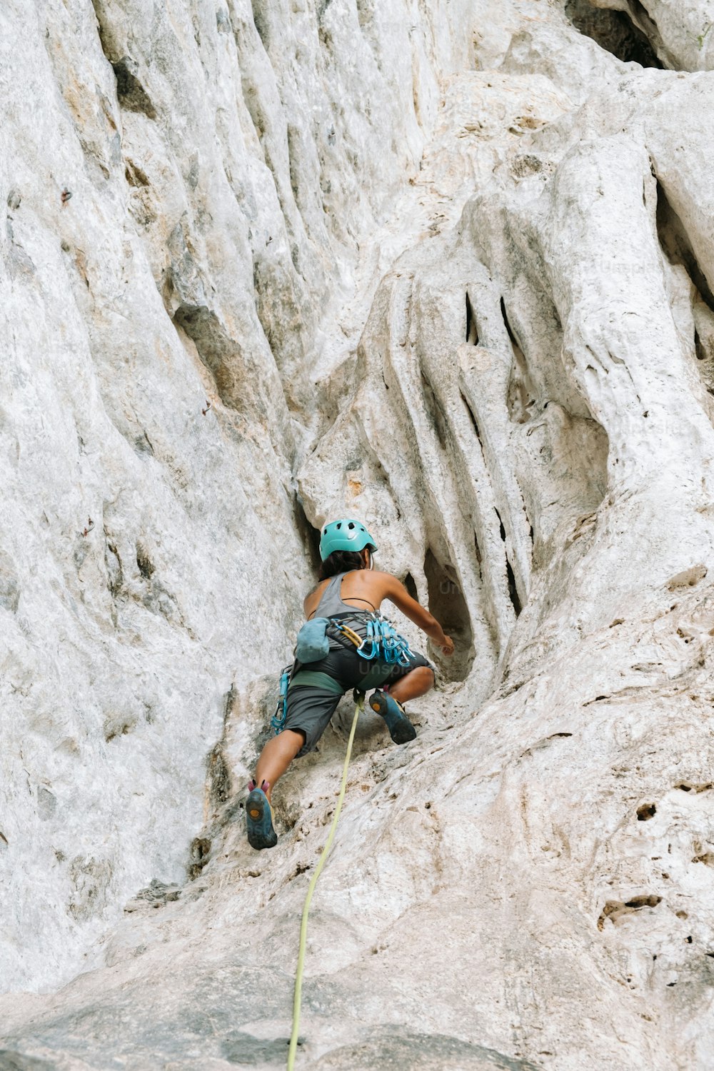 a woman climbing up the side of a mountain