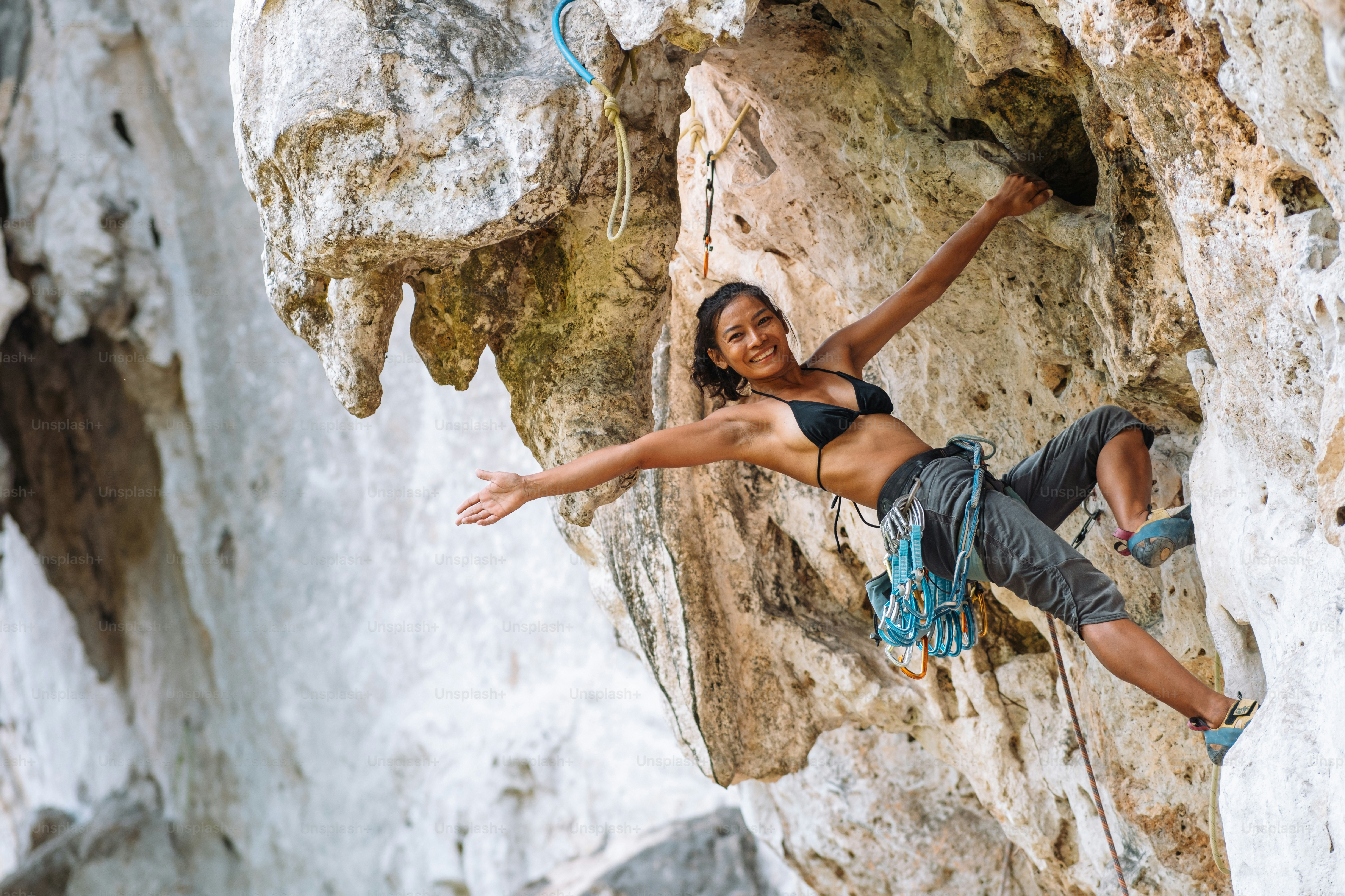 a woman climbing up the side of a mountain
