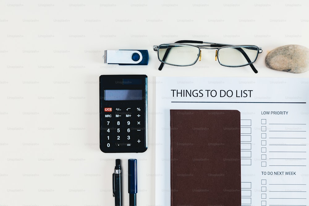 a desk with a calculator, pen, eyeglasses, and a