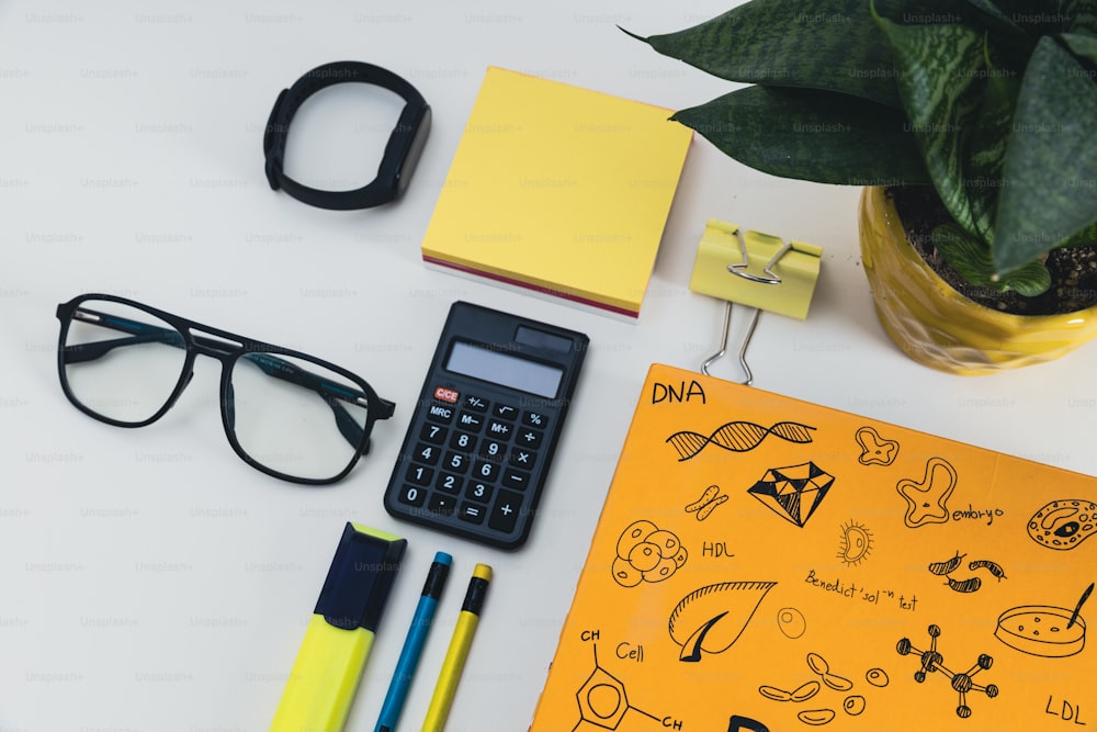 a desk with a calculator, notebook, pen, glasses, and a