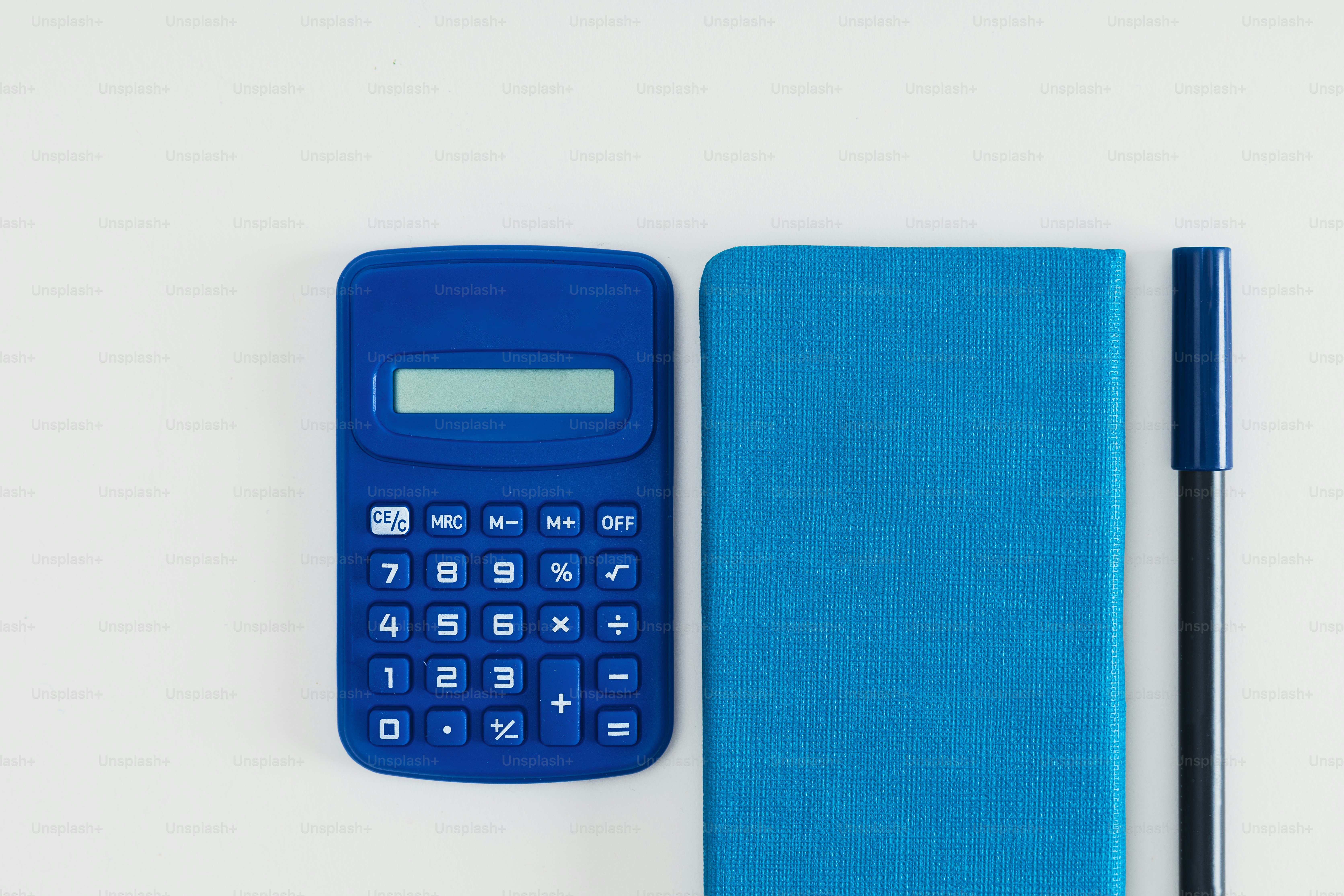 a blue calculator next to a notebook and pen