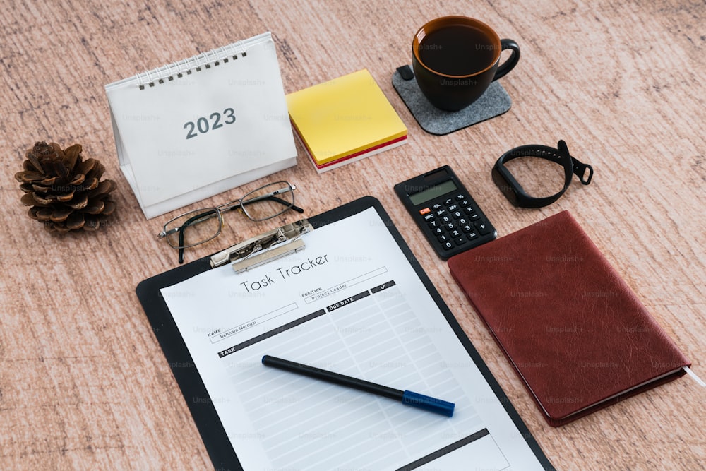 a desk with a notepad, pen, glasses and a cup of coffee