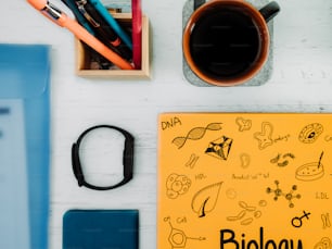 a desk with a notebook, pen, pencils, and a cup of coffee