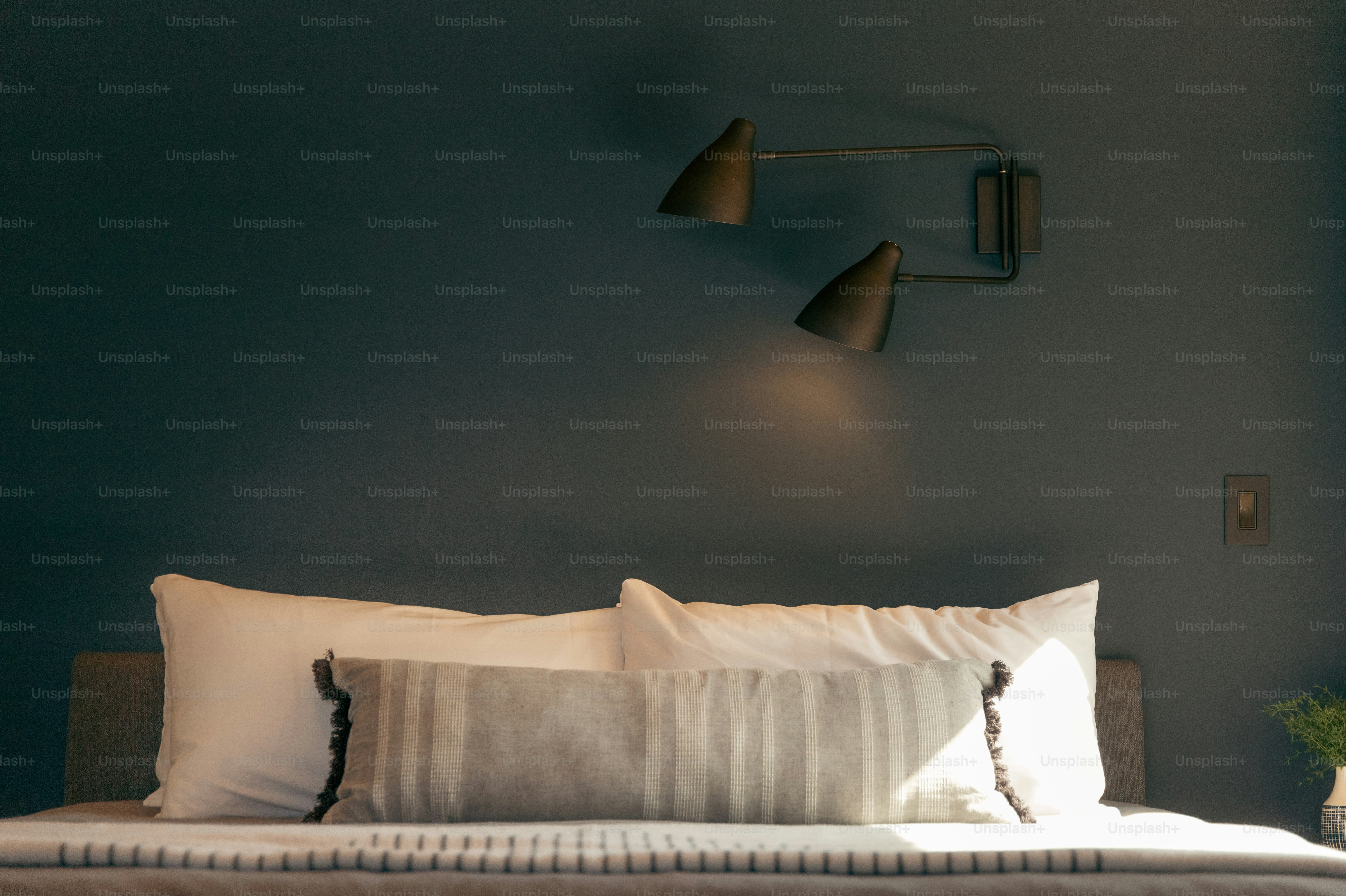 a bed with two lamps on the wall above it