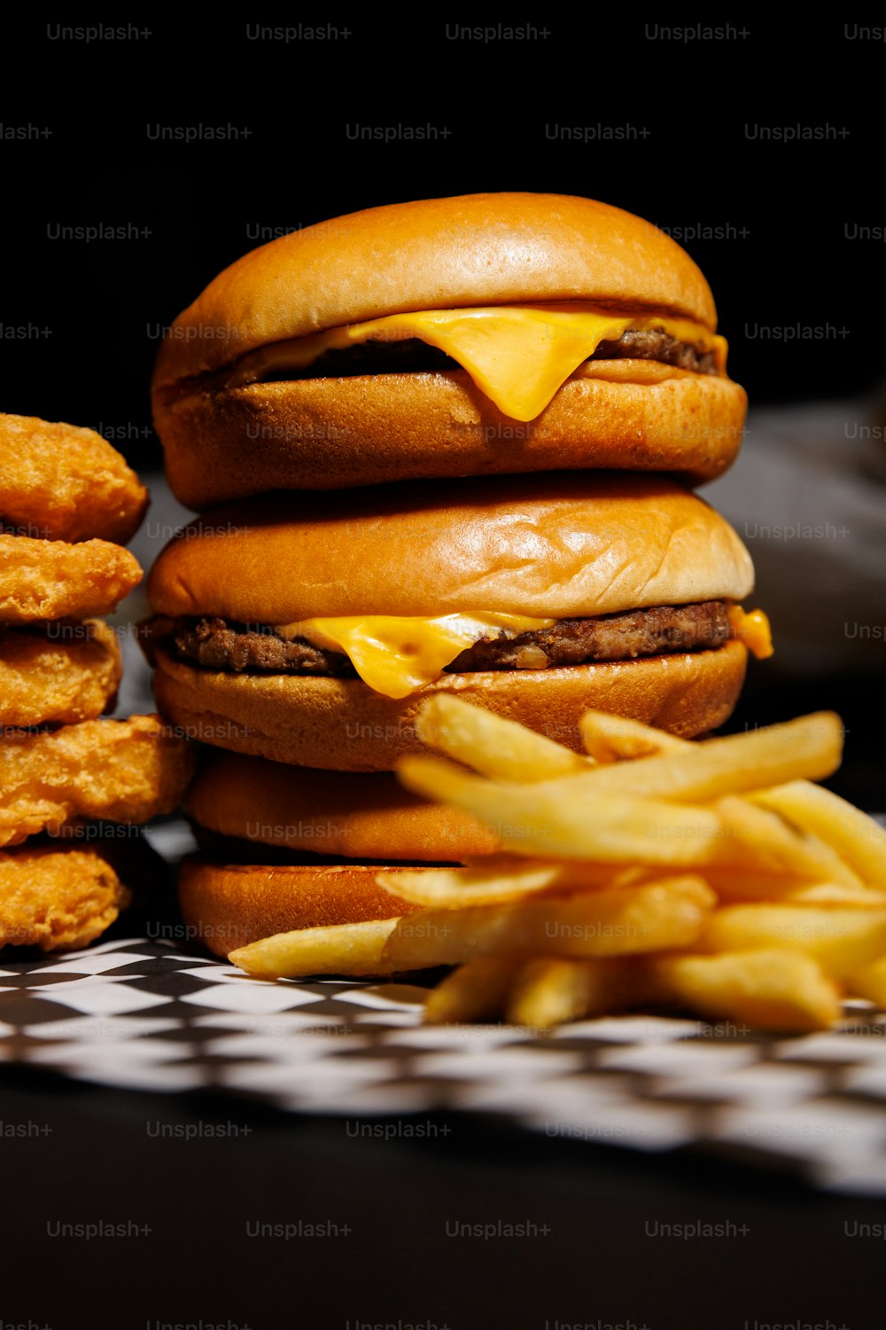 a stack of hamburgers sitting next to a pile of fries