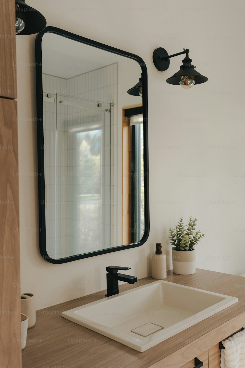 un lavandino del bagno seduto sotto un grande specchio