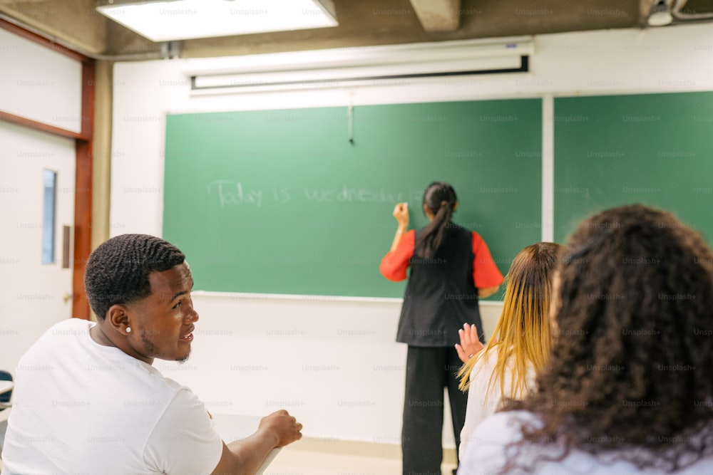 a man standing in front of a blackboard in a classroom