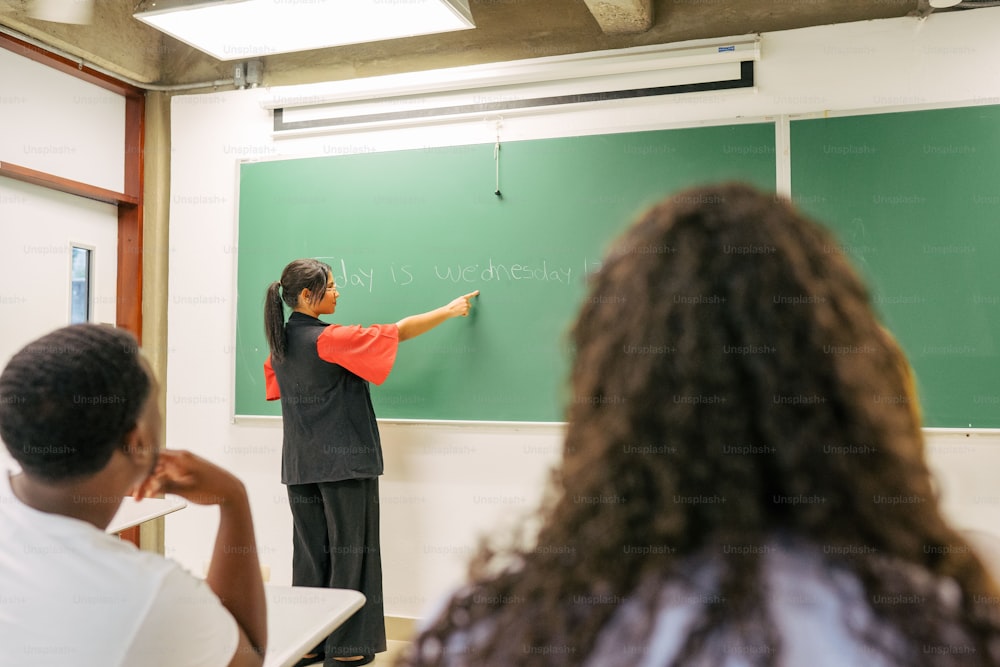 a woman standing in front of a blackboard writing on it