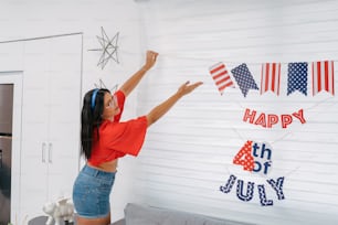 a woman in a red shirt and blue shorts holding up a fourth of july banner