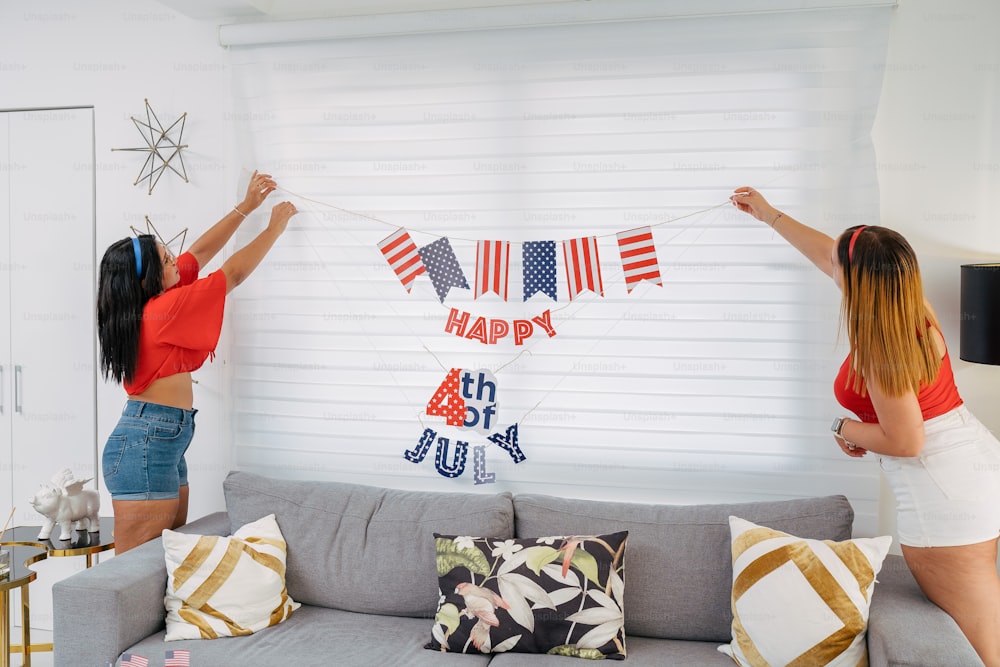 two women hanging a happy 4th of july banner