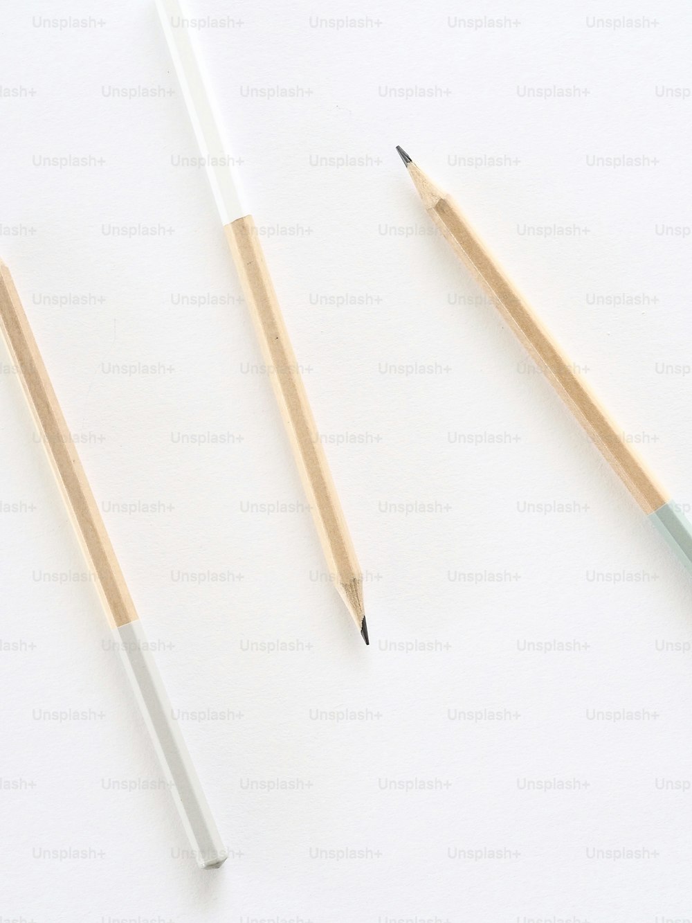 zwei Bleistifte und ein Bleistiftspitzer auf weißer Fläche