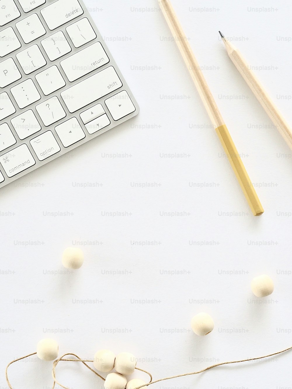un teclado, lápices y bolas de hilo sobre una superficie blanca