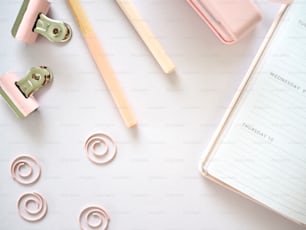 a desk with a binder, pencils, and paper clips