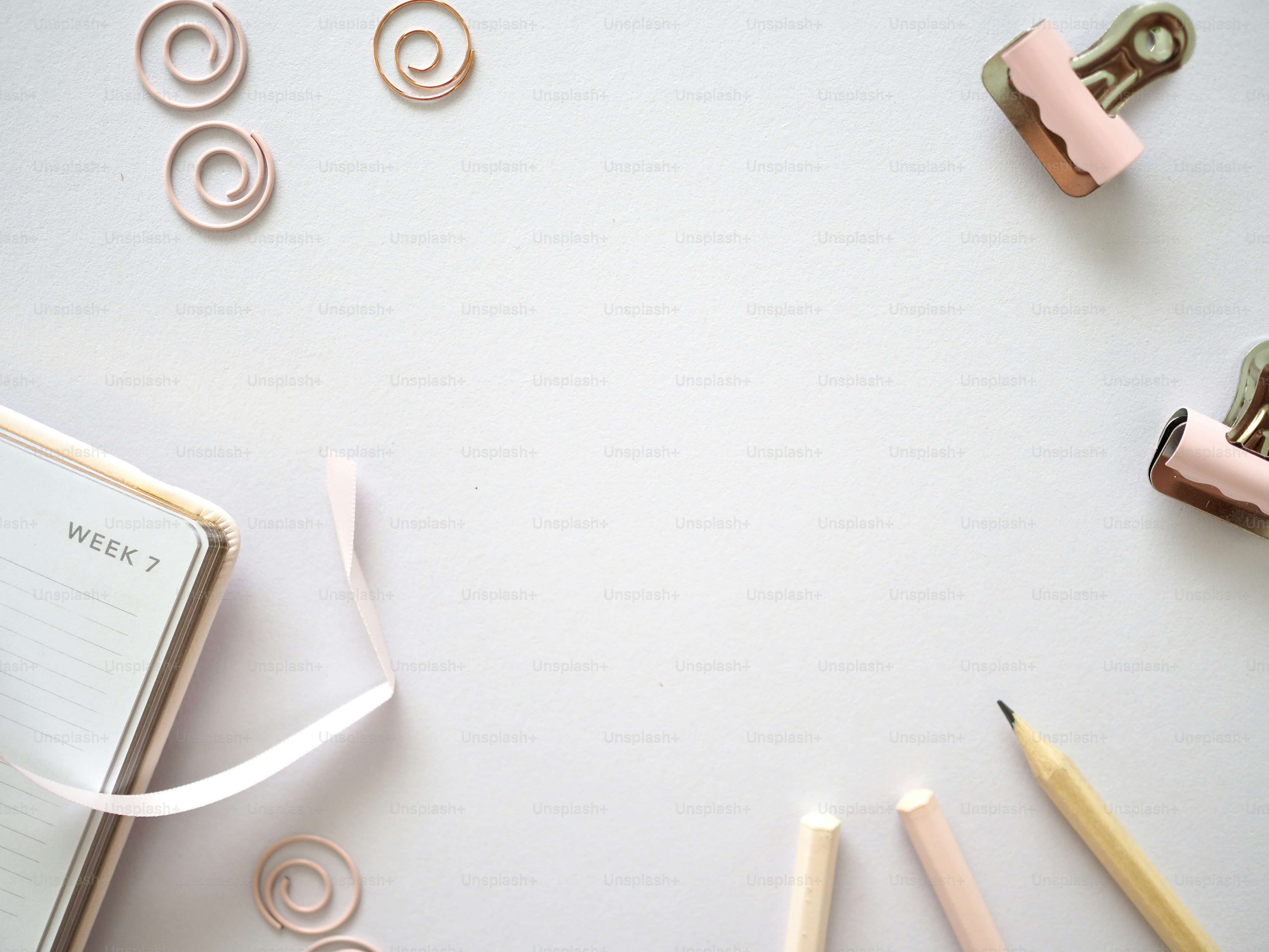 une table blanche surmontée d’un cahier et de crayons