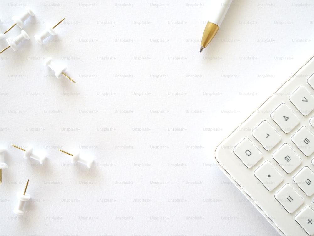 um teclado e uma caneta em uma superfície branca