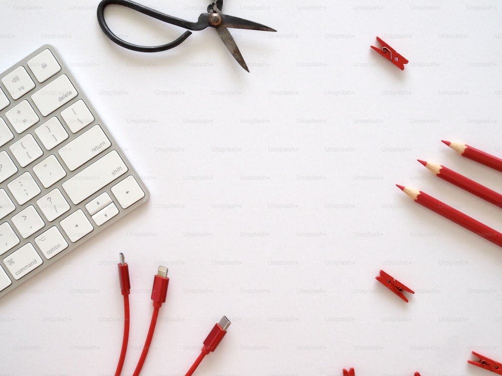 una tastiera, forbici, matite e un paio di forbici su un bianco
