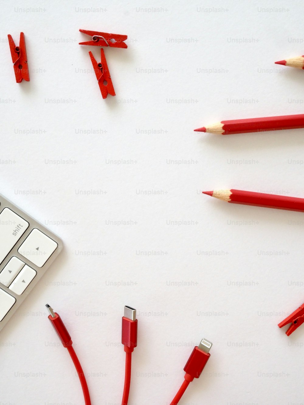 una tastiera e alcune matite rosse su una superficie bianca