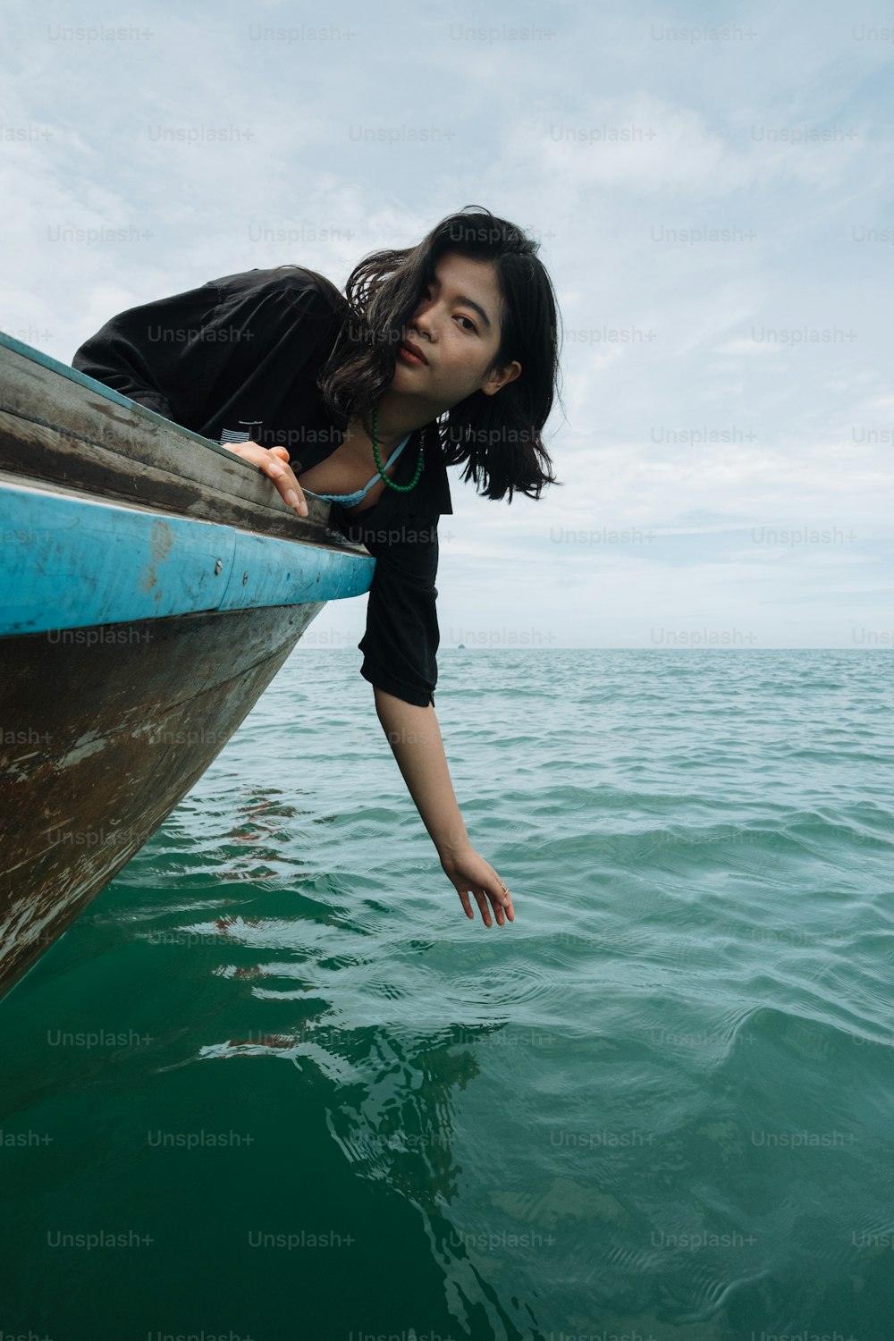 a woman leaning over the edge of a boat in the water