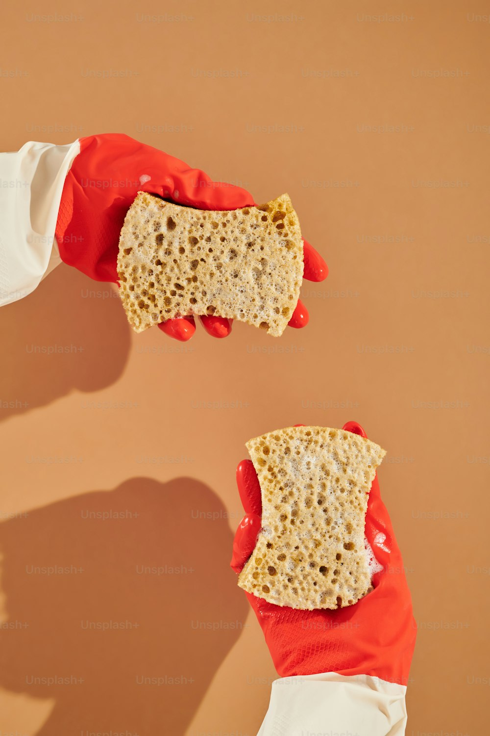 two hands in red gloves holding a piece of bread