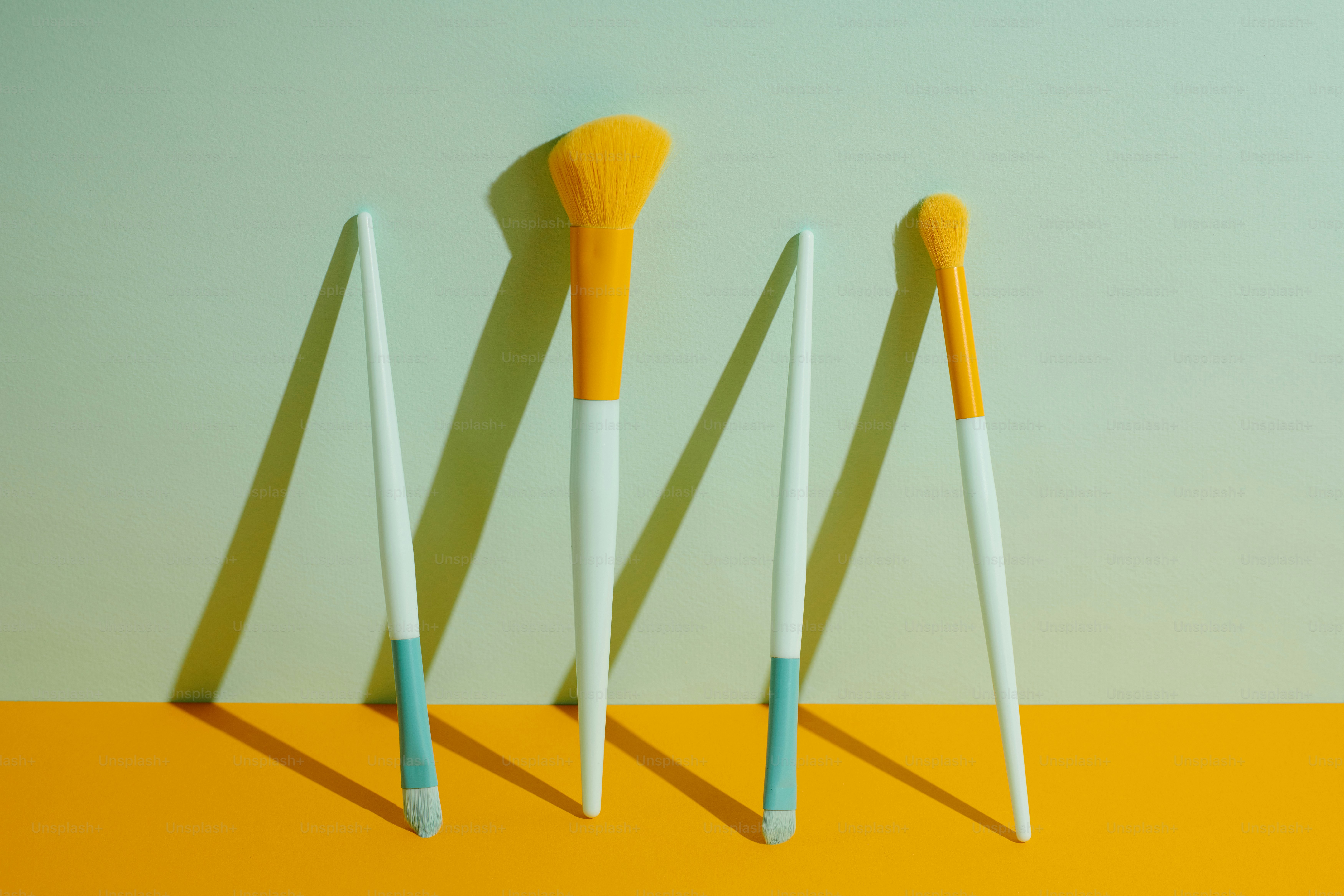 Un grupo de tres pinceles sentados encima de una mesa amarilla