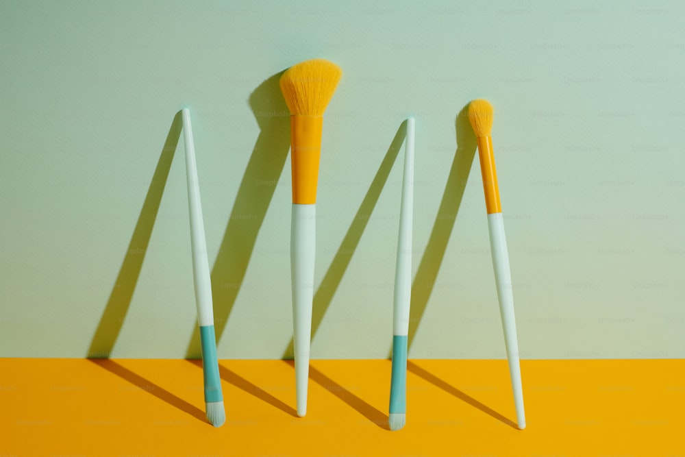 a group of three brushes sitting on top of a yellow table