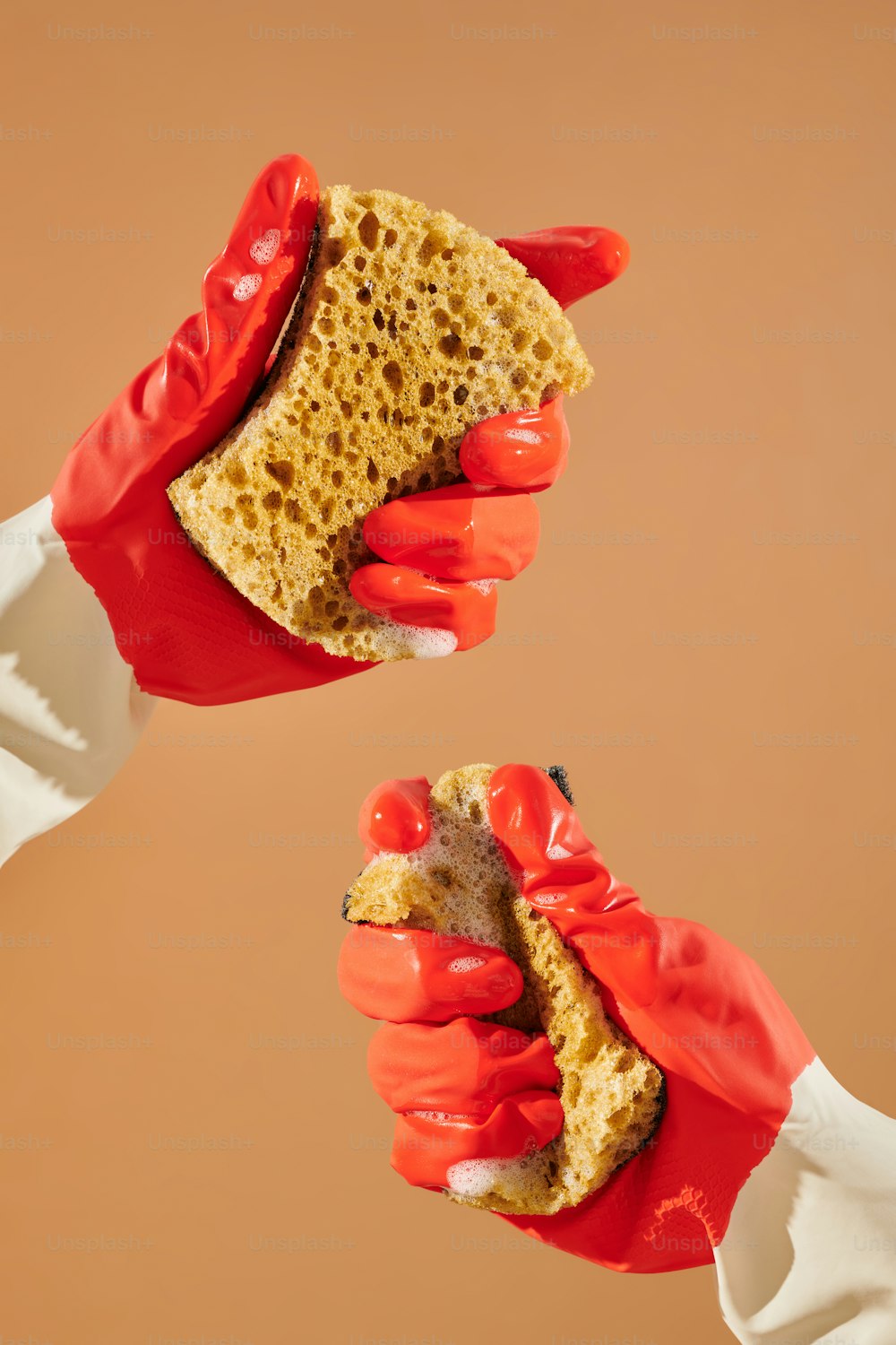 two hands in red gloves holding a piece of bread