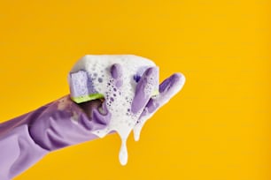 a hand in purple gloves holding a sponge