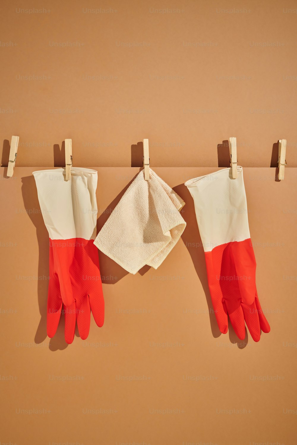 ein Paar rot-weiße Handschuhe, die an einer Wäscheleine hängen