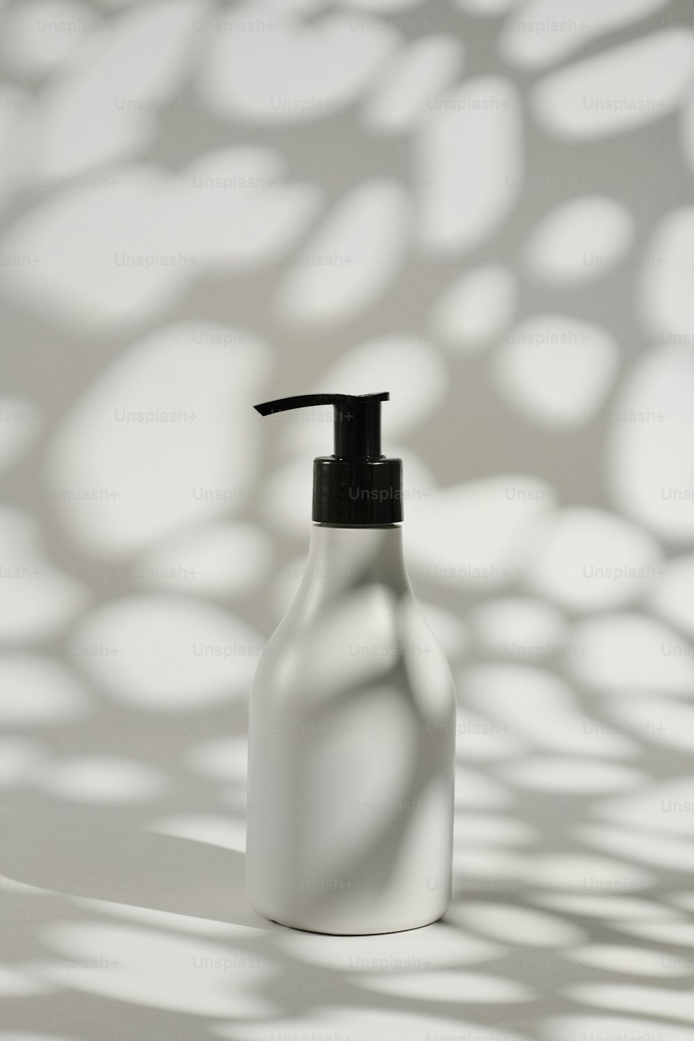 une bouteille blanche avec un couvercle noir sur une surface blanche