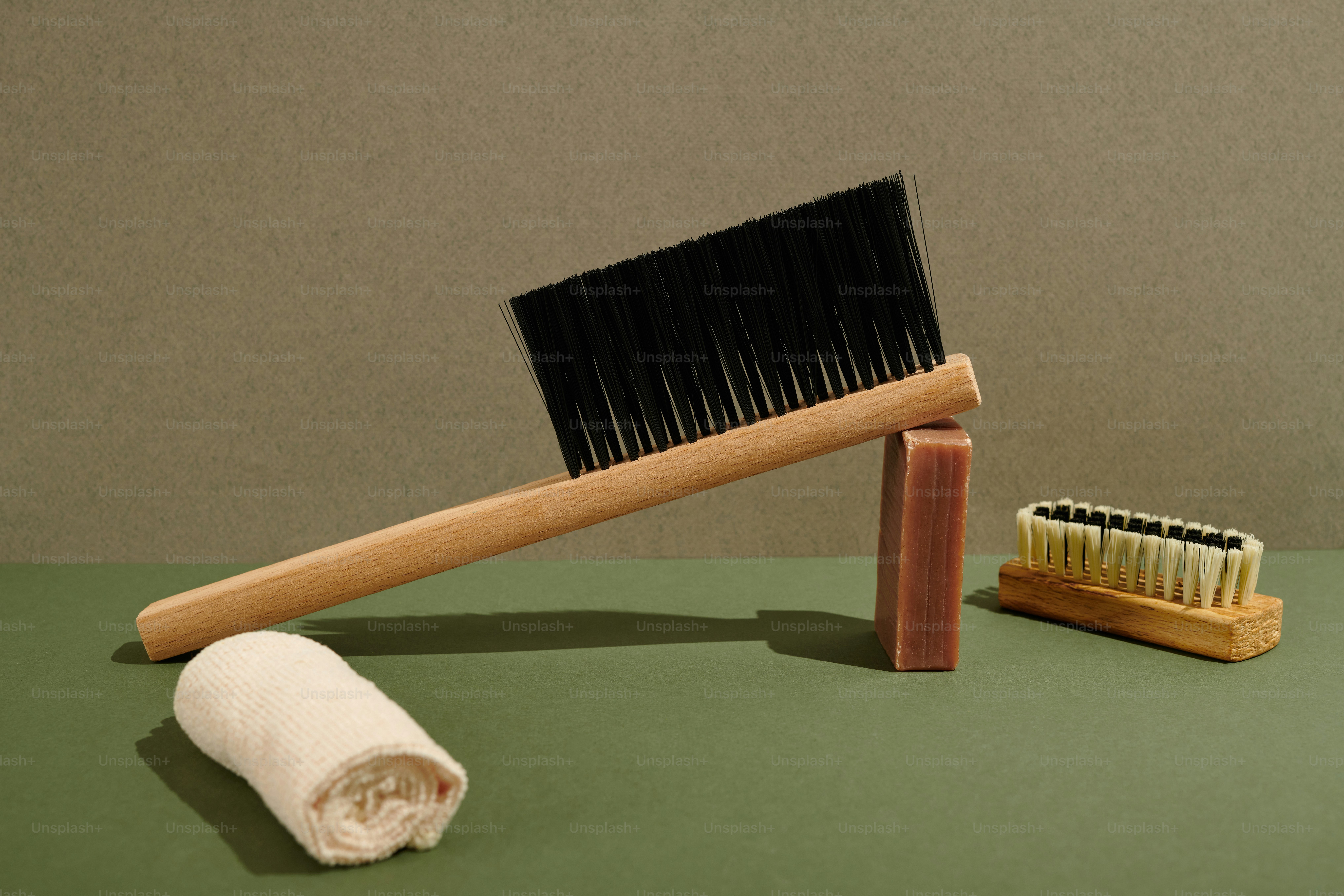 une brosse en bois et une serviette blanche sur une surface verte