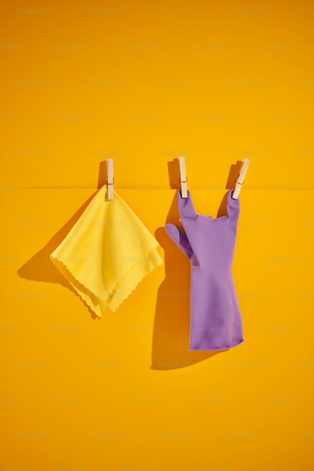 Kleidung, die an Wäscheklammern auf gelbem Hintergrund hängt