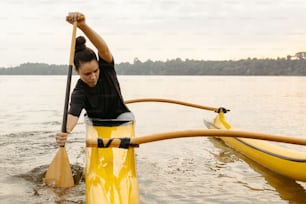 Una mujer con una camisa negra remando en un kayak amarillo