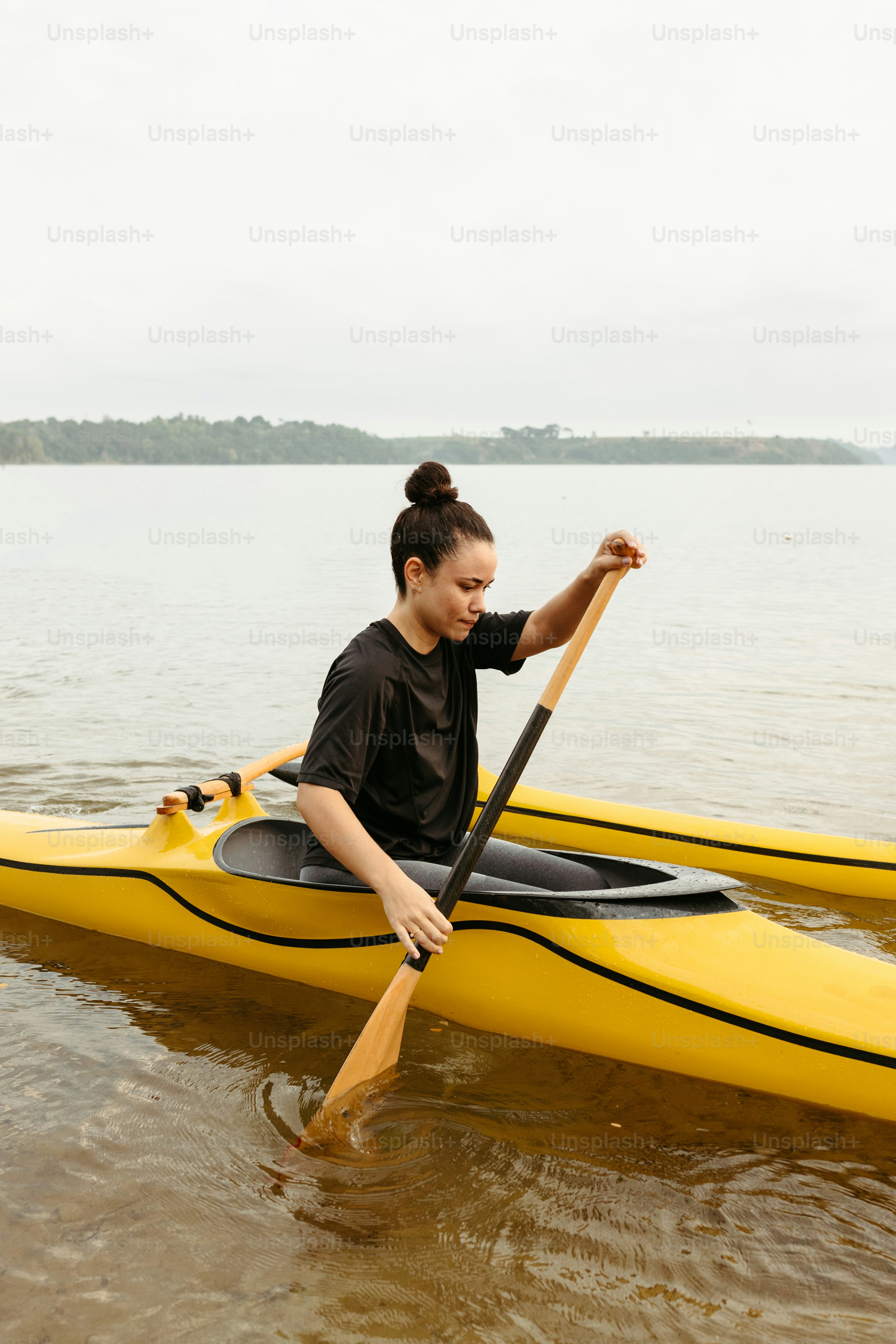 a woman sitting on a yellow kayak in the water