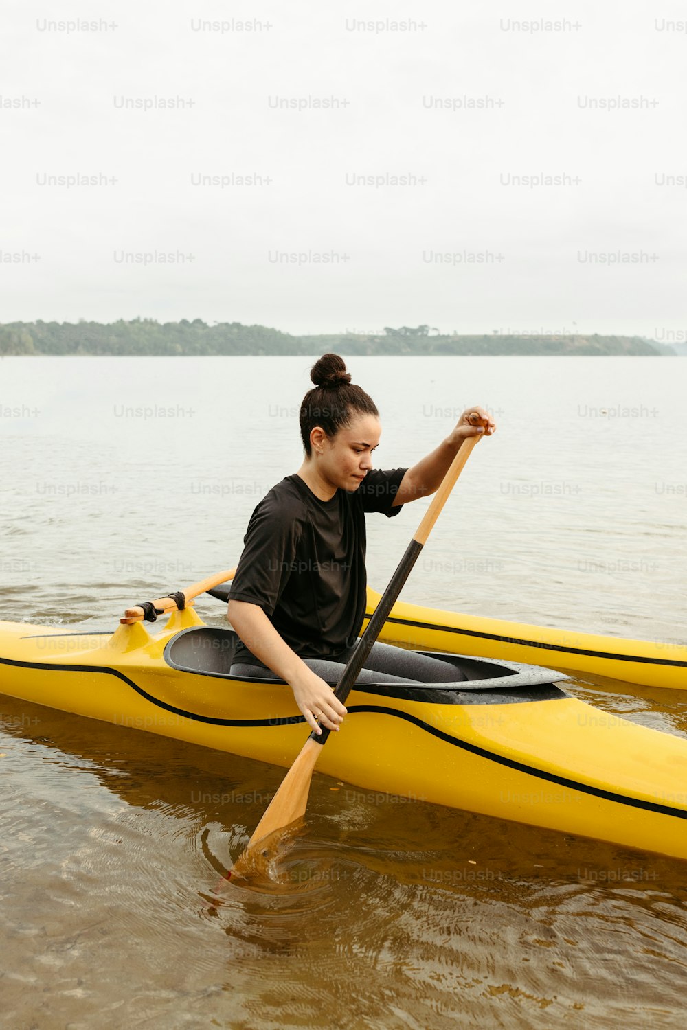 uma mulher sentada em um caiaque amarelo na água