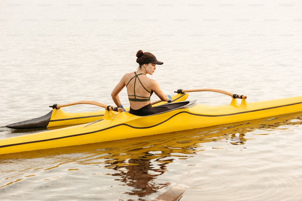 a woman in a bikini paddling a yellow kayak