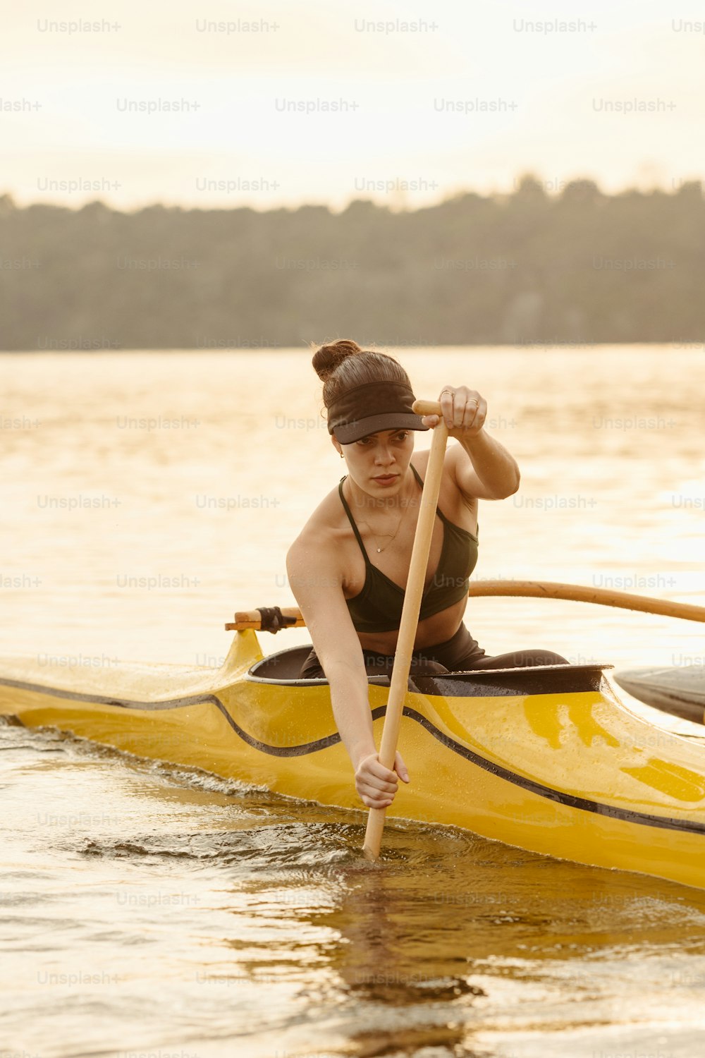 Una mujer remando un kayak amarillo en un lago