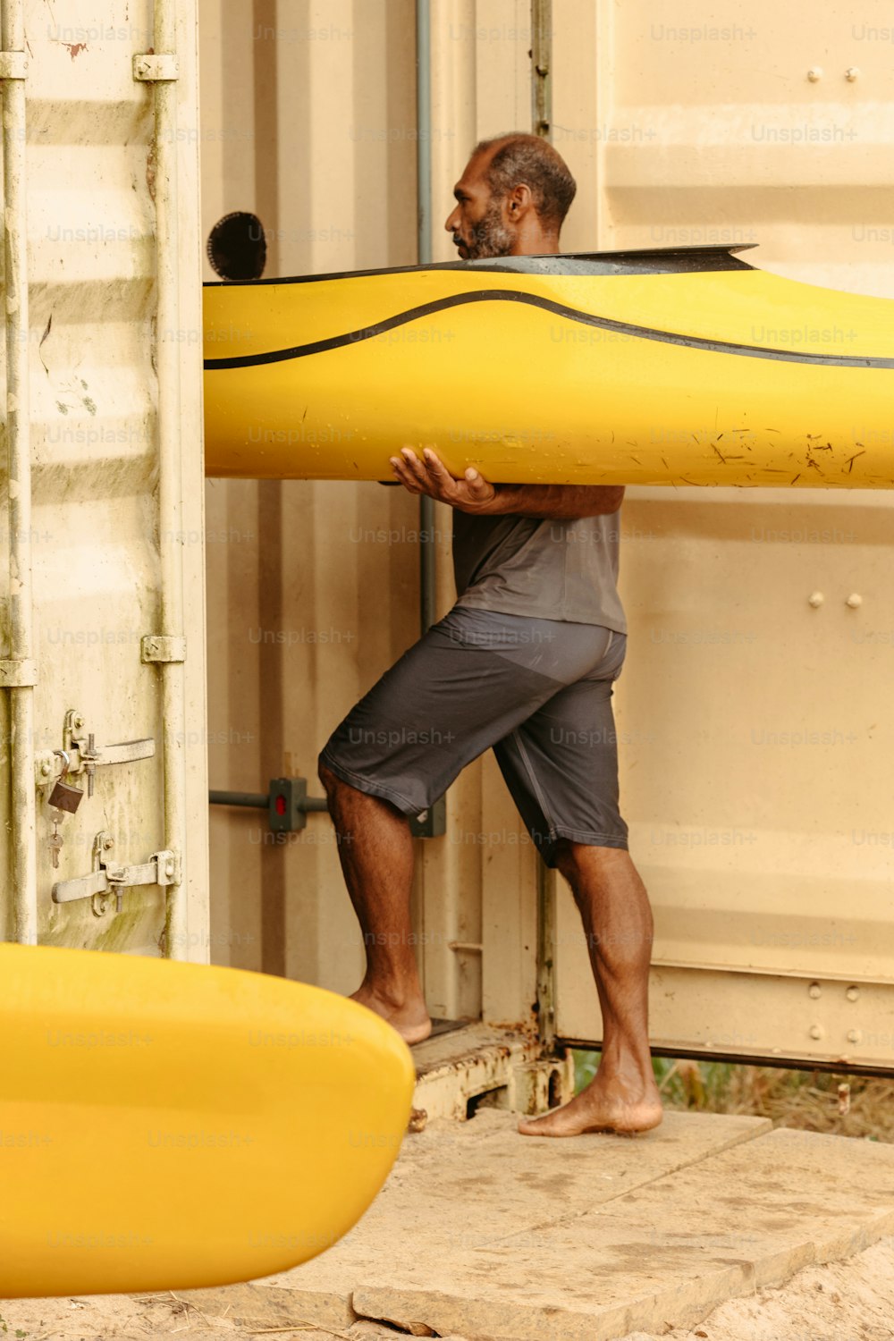 a man carrying a large yellow surf board